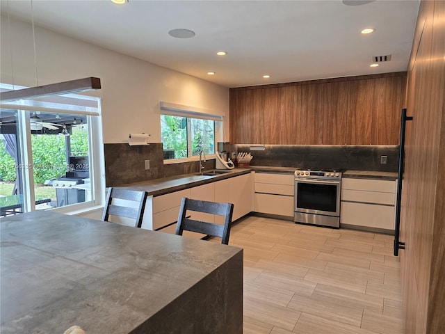 kitchen with visible vents, dark countertops, gas range, modern cabinets, and a sink