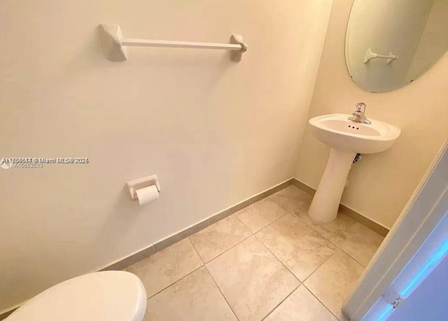 bathroom with tile patterned flooring, toilet, and baseboards