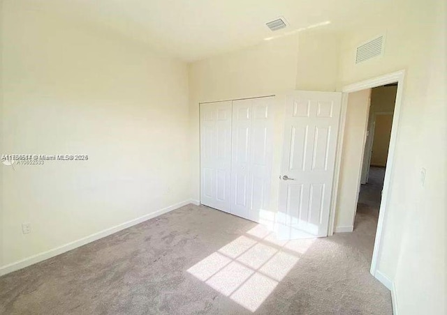 unfurnished bedroom with carpet, a closet, visible vents, and baseboards