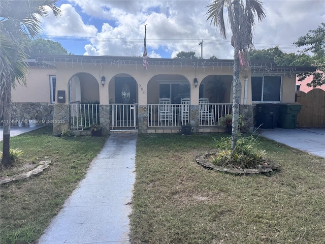 view of front facade with covered porch, a front lawn, and stucco siding