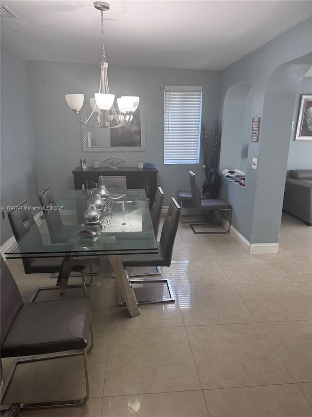 dining area with visible vents, arched walkways, baseboards, tile patterned flooring, and a notable chandelier