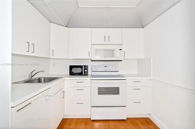 kitchen featuring white appliances, light wood-style flooring, light countertops, and a sink