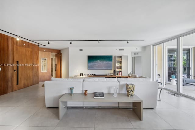 living area with a wall of windows, visible vents, and light tile patterned floors