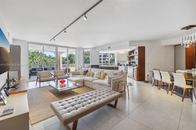 living area with expansive windows, rail lighting, and a notable chandelier