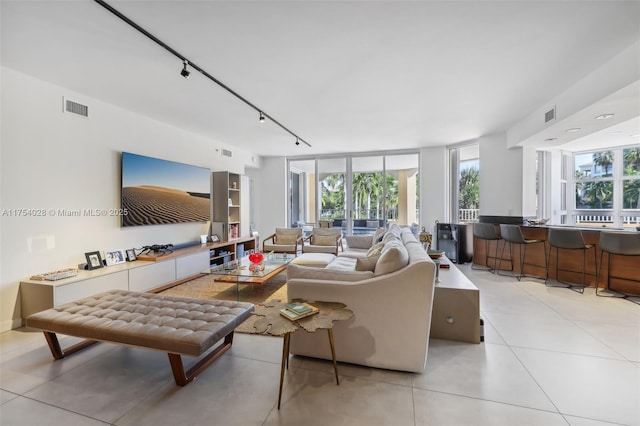 living area with light tile patterned flooring, rail lighting, visible vents, and floor to ceiling windows