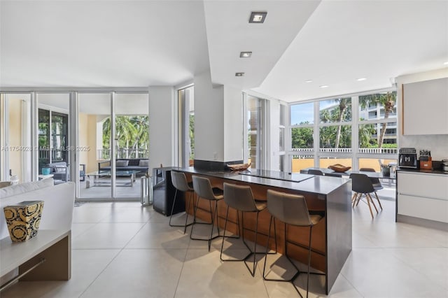 kitchen with modern cabinets, expansive windows, a breakfast bar area, and light tile patterned flooring