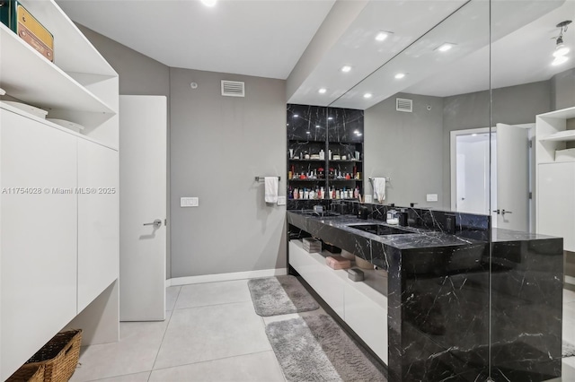 bathroom featuring baseboards, a sink, visible vents, and tile patterned floors