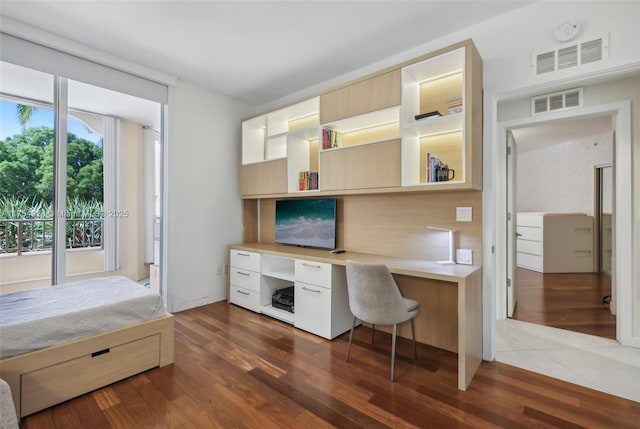 office space featuring built in desk, wood finished floors, and visible vents