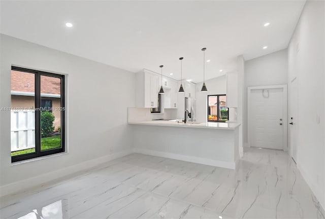 kitchen with baseboards, light countertops, a peninsula, and white cabinets