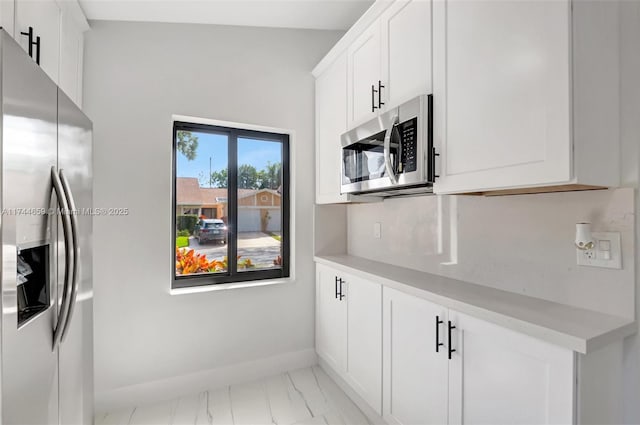 kitchen featuring marble finish floor, appliances with stainless steel finishes, light countertops, and baseboards