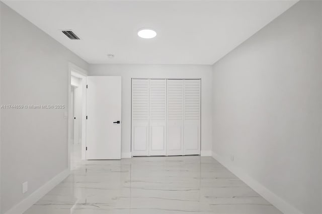 unfurnished bedroom with marble finish floor, a closet, visible vents, and baseboards