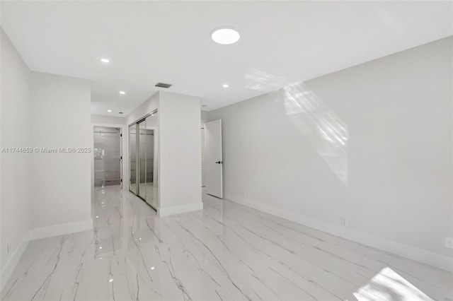 spare room featuring a barn door, visible vents, baseboards, and recessed lighting