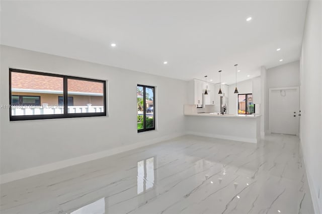 unfurnished living room featuring lofted ceiling, marble finish floor, baseboards, and recessed lighting