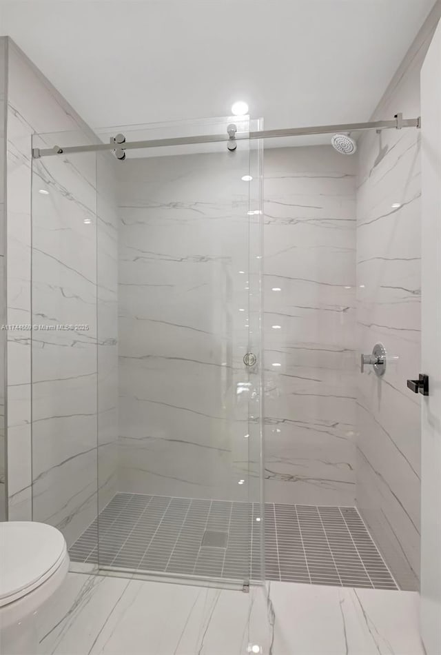 bathroom with toilet and a marble finish shower