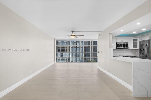 interior space featuring ceiling fan, expansive windows, baseboards, and recessed lighting