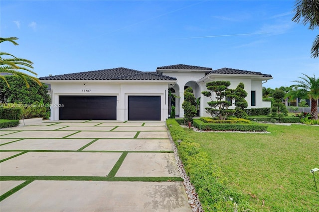 view of front of property featuring driveway, a tiled roof, an attached garage, a front lawn, and stucco siding