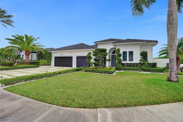 view of front facade with concrete driveway, a tiled roof, an attached garage, a front yard, and stucco siding