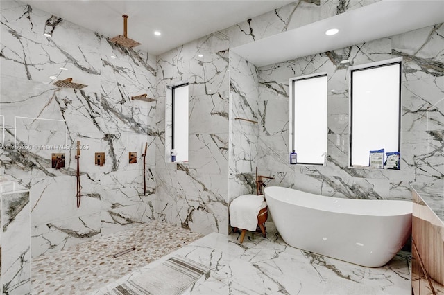 bathroom featuring recessed lighting, a soaking tub, a marble finish shower, and stone wall