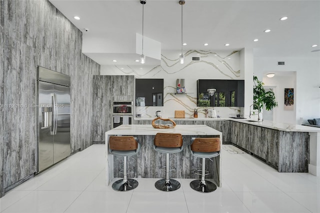 kitchen featuring built in fridge, a breakfast bar, light stone counters, light tile patterned floors, and modern cabinets