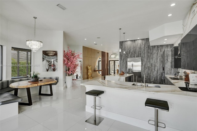 kitchen with light tile patterned floors, modern cabinets, light stone counters, pendant lighting, and built in fridge