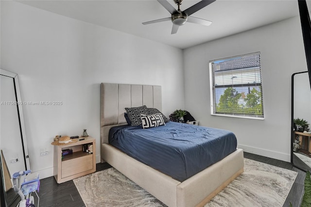 bedroom with dark wood-type flooring, a ceiling fan, and baseboards