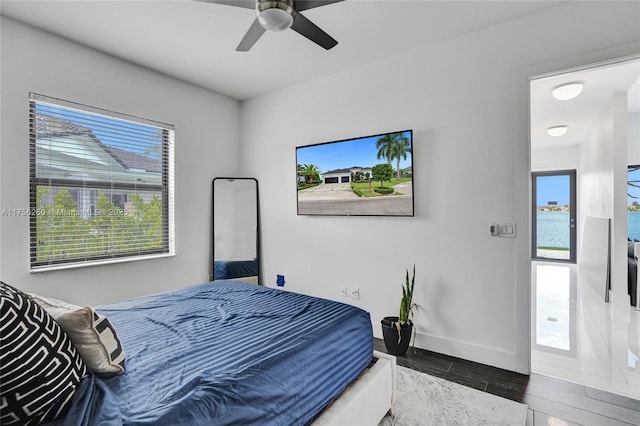 bedroom with ceiling fan, baseboards, and wood finished floors