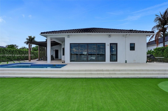 rear view of property with a fenced in pool, a patio, stucco siding, a lawn, and a tiled roof