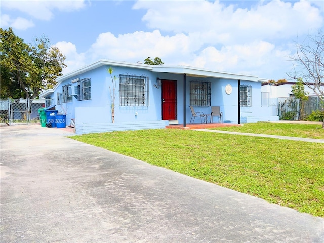 view of front of property featuring concrete driveway, a front lawn, and fence