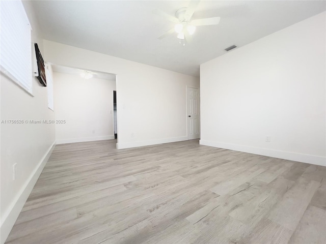 empty room with ceiling fan, light wood-type flooring, visible vents, and baseboards