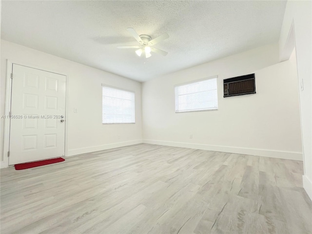 spare room with light wood-type flooring, ceiling fan, a textured ceiling, and baseboards