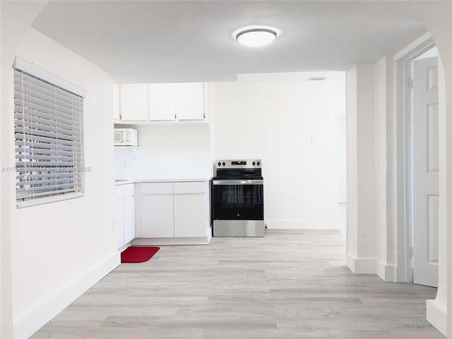 kitchen featuring white microwave, white cabinetry, light wood-style floors, and stainless steel range with electric cooktop