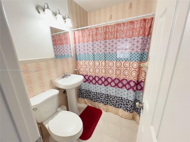 bathroom featuring toilet, curtained shower, tile patterned flooring, and tile walls