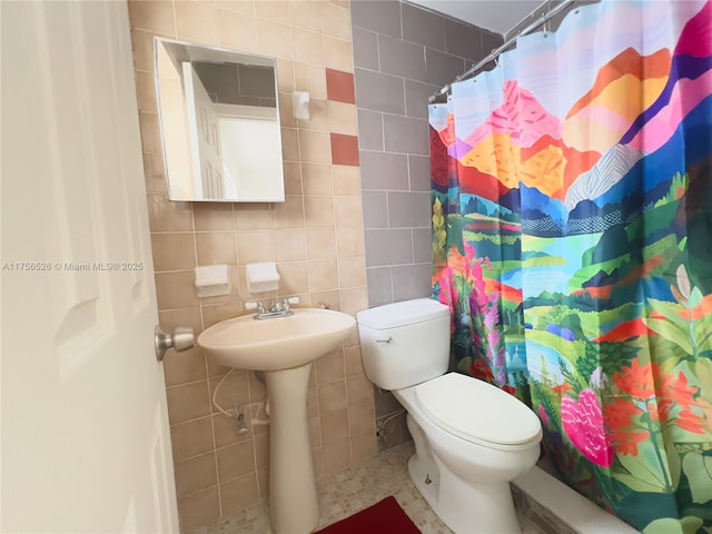 full bathroom with toilet, a shower with curtain, and tile walls