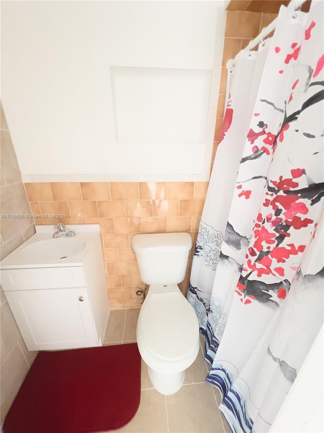 full bath featuring a shower with shower curtain, toilet, tile patterned flooring, vanity, and tile walls