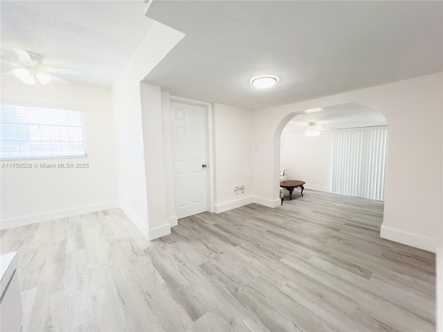 unfurnished room featuring arched walkways, ceiling fan, baseboards, and wood finished floors