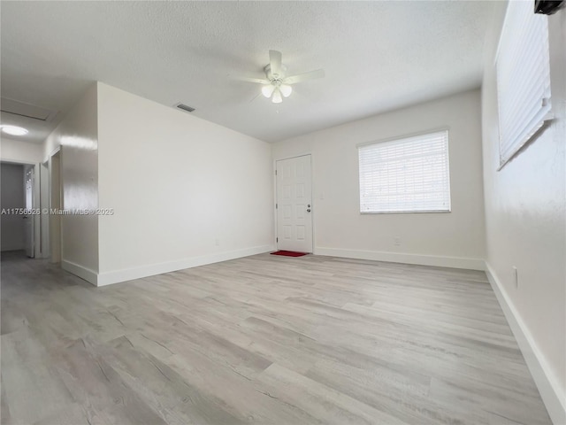 empty room featuring visible vents, ceiling fan, a textured ceiling, light wood-type flooring, and baseboards