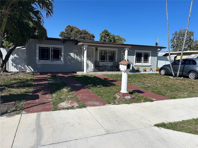 view of front of property with a front lawn, fence, and stucco siding