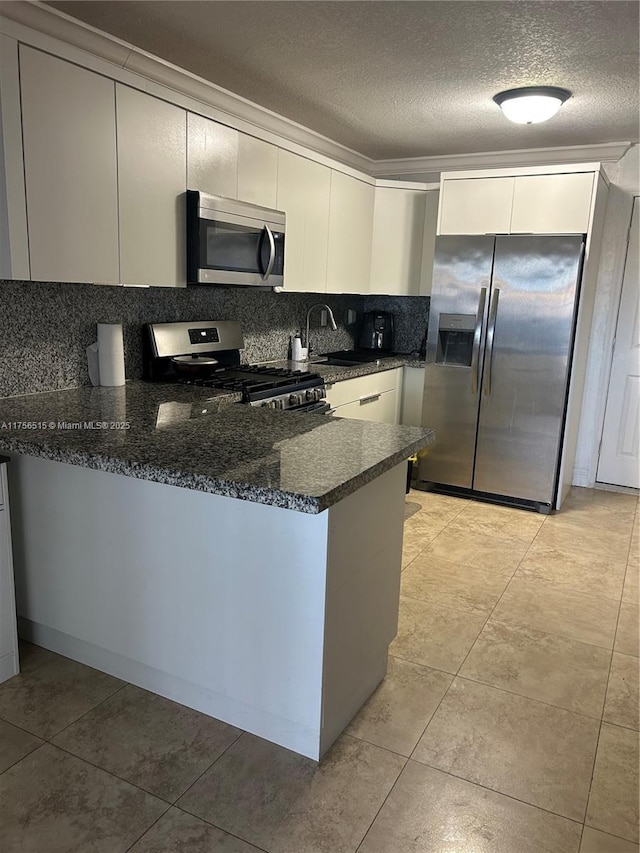 kitchen with appliances with stainless steel finishes, backsplash, a peninsula, a textured ceiling, and a sink