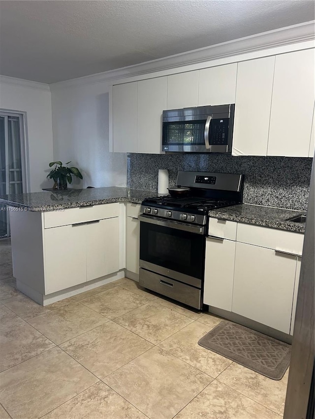 kitchen with stainless steel appliances, tasteful backsplash, ornamental molding, dark stone countertops, and a peninsula