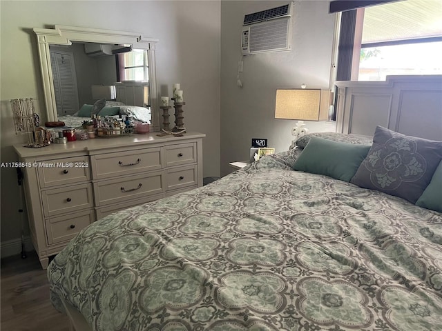 bedroom with multiple windows, wood finished floors, and a wall mounted AC