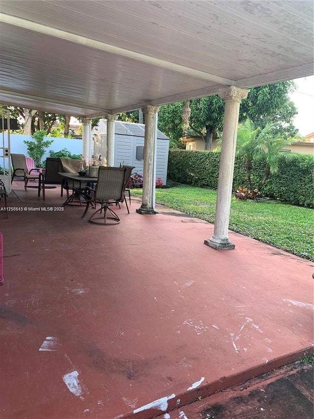 view of patio / terrace with a storage shed, outdoor dining space, and an outbuilding