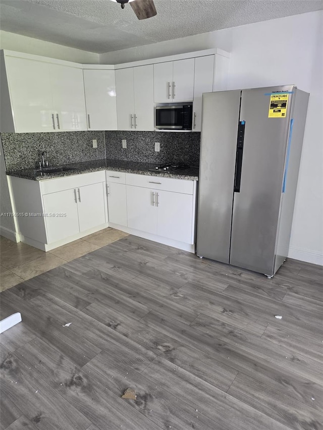 kitchen with a textured ceiling, ceiling fan, white cabinets, appliances with stainless steel finishes, and backsplash