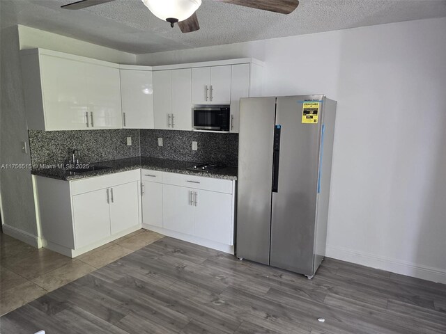 kitchen featuring appliances with stainless steel finishes, a sink, white cabinetry, and tasteful backsplash