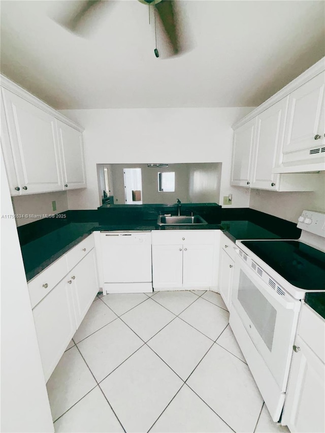 kitchen featuring white appliances, dark countertops, under cabinet range hood, white cabinetry, and a sink