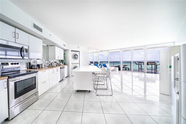 6301 Collins Ave Unit 2802, Miami Beach, FL 33141 - kitchen featuring appliances with stainless steel finishes, estacked washer and dryer, a breakfast bar, white cabinets, and light countertops