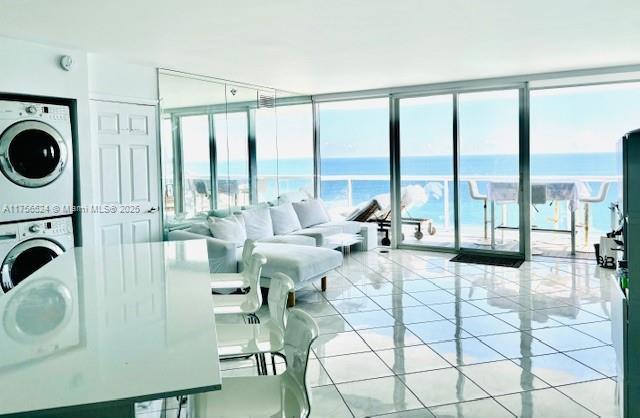 6301 Collins Ave Unit 2802, Miami Beach, FL 33141 - living area with stacked washer and clothes dryer, floor to ceiling windows, light tile patterned floors, and a water view