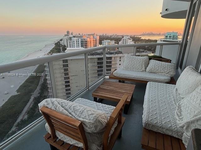 balcony at dusk featuring a water view and a city view