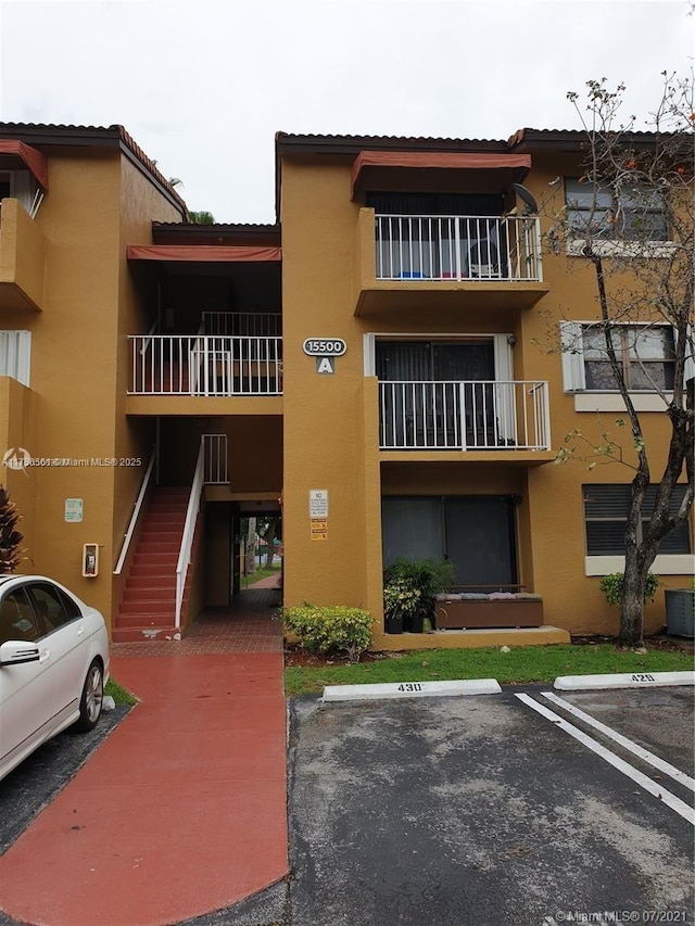 view of building exterior featuring uncovered parking and stairs