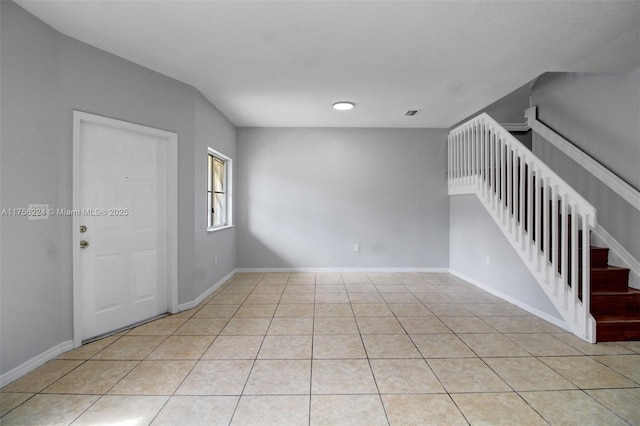 unfurnished room featuring stairs, light tile patterned floors, and baseboards