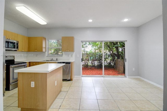 kitchen featuring light tile patterned floors, a kitchen island, appliances with stainless steel finishes, light countertops, and a sink